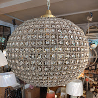  large, aged brass crystal globe chandelier with crystal beading encased in brass metalwork that reflects a pretty pattern around your ceiling and walls. 