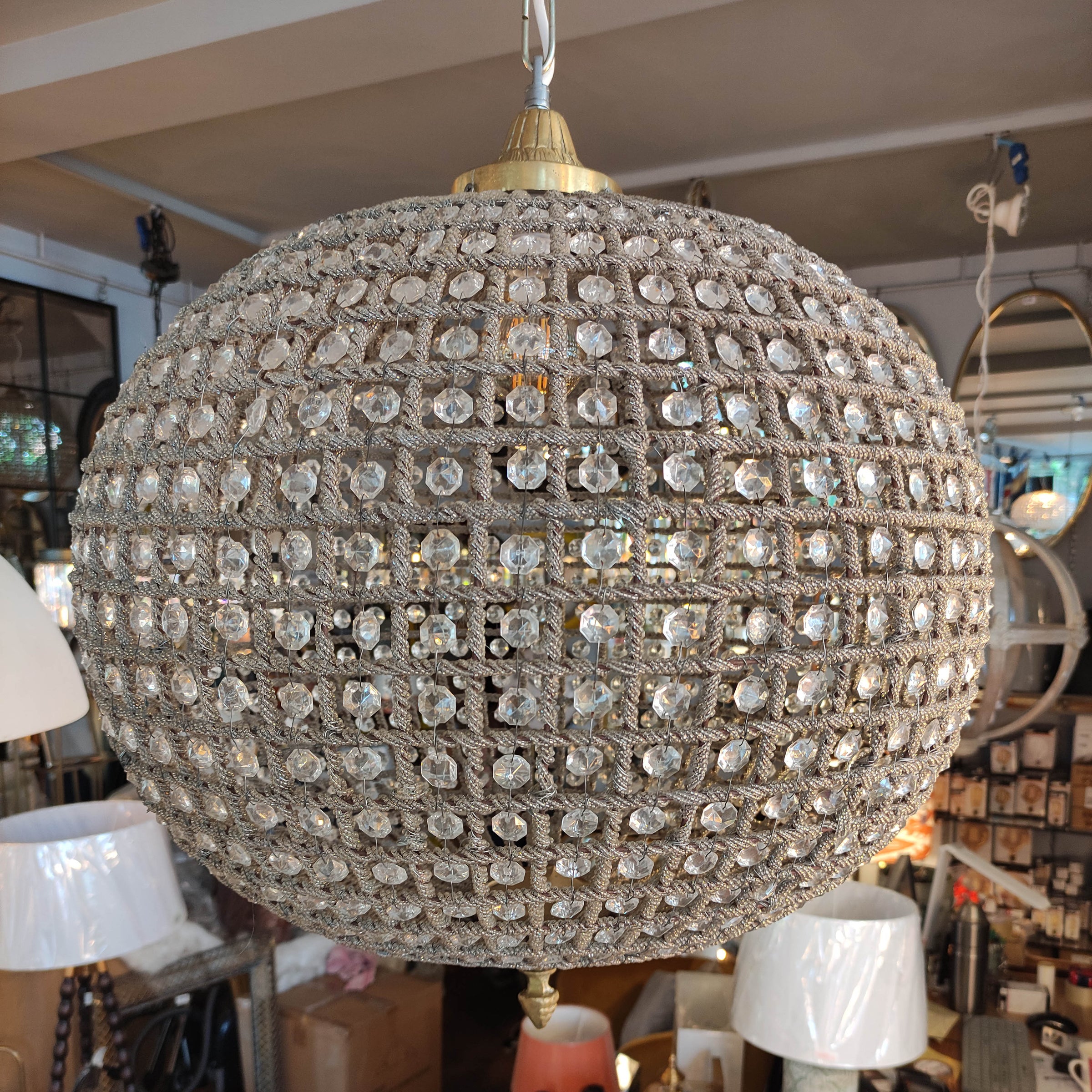  large, aged brass crystal globe chandelier with crystal beading encased in brass metalwork that reflects a pretty pattern around your ceiling and walls. 