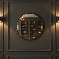 A huge, very distressed black convex mirror on a panelled wall.