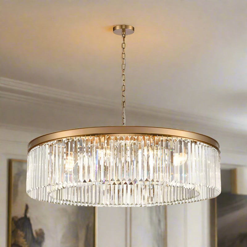 This chandelier pairs a smooth gold band with rows of shimmering prism-cut crystals, creating a striking, luxurious glow. With its impressive 100 cm width
