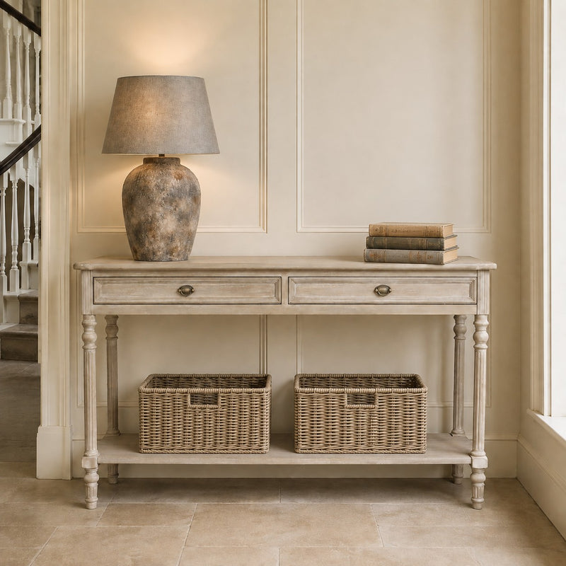 Stone lamp base with weathered finish and a grey linen shade on a distressed cream console table in a classic home interior