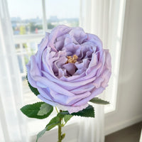 This ultra-realistic artificial lilac rose features rich, velvet-like petals and a vibrant green stem with textured leaves