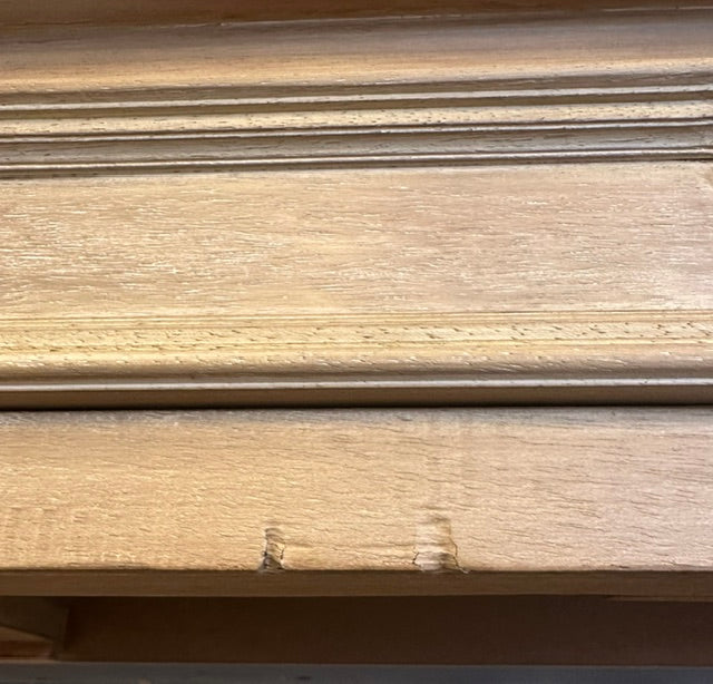 Close-up of a light natural wood surface with visible grain and a horizontal grooved line across the top.