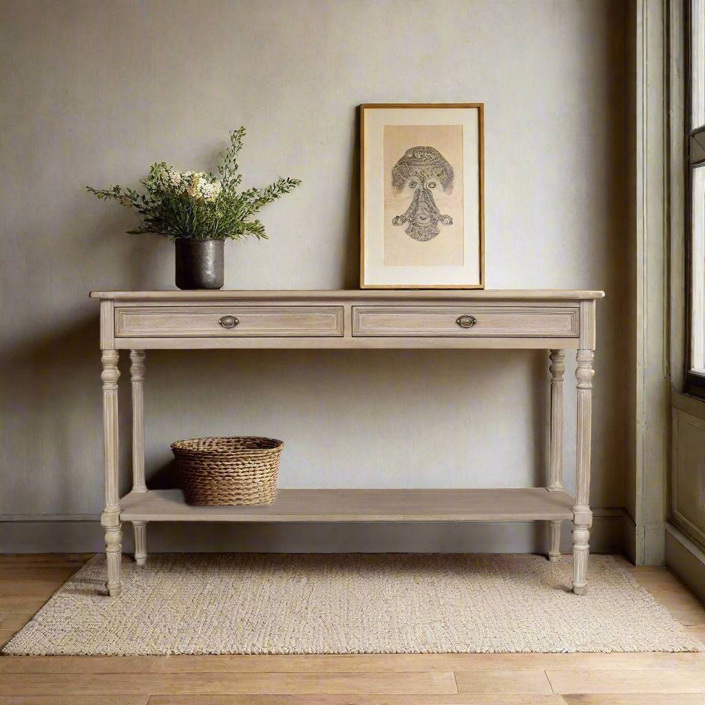 Limewashed wooden console table with turned legs, lower storage shelf and vintage-style drawer pulls in a rustic country-style finish.