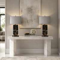 Black veined marble table lamp with grey linen oval shade, gold accents, placed on a white marble console table in a modern interior.