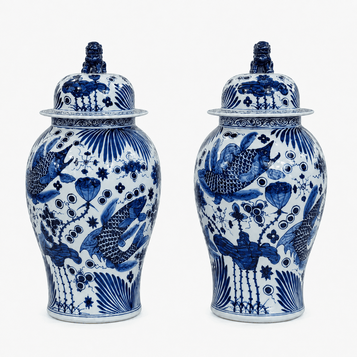 Pair of medium blue and white glazed ginger jars decorated with fish, aquatic plants and floral motifs, each with a domed lid and blue guardian-lion finial.