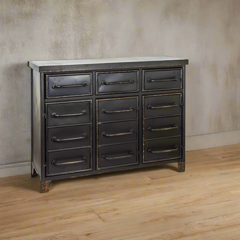 Metal chest drawers, with lower faux drawers consisting of three doors opening on to shelving, on a wooden floor against a limewashed wall.