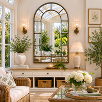 Dark gold metal framed window mirror in a conservatory setting with lamp and wall lighting. 