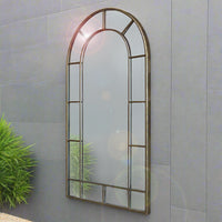 Arched window mirror on a grey outdoor wall