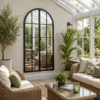 Grey arched window mirror with 'opening door' feature, in a conservatory setting with conservatory furniture and lighting. 