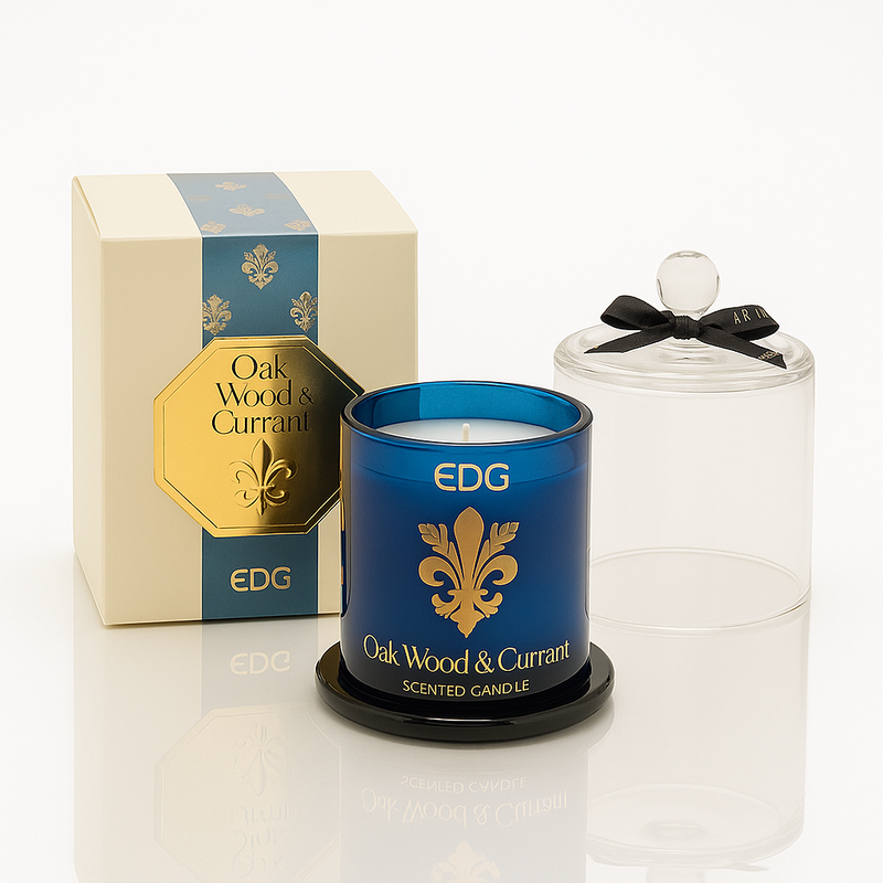 Oak Wood & Currant luxury scented candle in deep blue glass with gold detailing and a clear cloche, presented in a matching gift box.