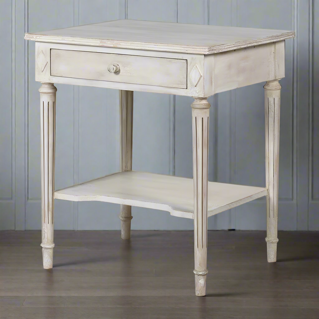 Off white classic one drawer bedside with lower shelf and reeded legs. This is a timeless table crafted individually to the highest quality and the perfect off white, pale grey washed colour that will suit so many interiors. Functional with a drawer and lower curved shelf.