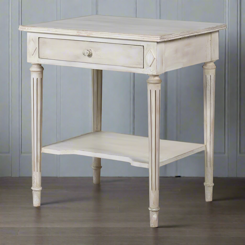 Off white classic one drawer bedside with lower shelf and reeded legs. This is a timeless table crafted individually to the highest quality and the perfect off white, pale grey washed colour that will suit so many interiors. Functional with a drawer and lower curved shelf.