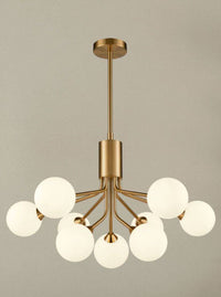 Opaque globe 9 ball chandelier with brushed brass arms and opal glass shades hanging from an adjustable rod