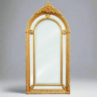 Extremely ornate arched gold mirror with beveled panels.