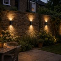 Three bi-directional lights, illuminating a city garden on the garden wall. 