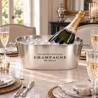 Single bottle of champagne in oval champagne bucket on a dining table.