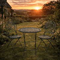 Three piece garden set, folding table and chairs in grey metal, set in garden at sunset.