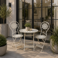 Three piece folding patio table and two chairs sitting in a modern patio with planters. 