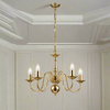 A polished brass classic chandelier with five branches and unlit candles.