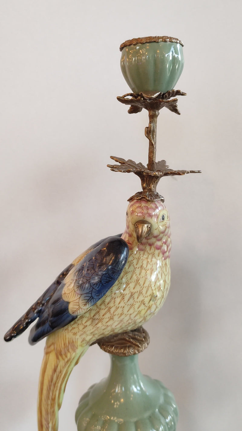 A pair of a colourful porcelain parrot candle holders with gilt bronze detailing. Crafted to exceptional quality, they add luxurious warmth and timeless charm to refined interiors