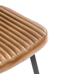 Ribbed tan leather dining chair with slim black iron legs and a contoured seat and back.