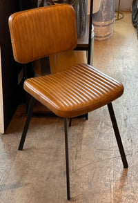 Ribbed tan leather dining chair with slim black iron legs and a contoured seat and back.