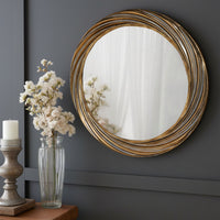 A round wall mirror with a distressed gold, deeply textured frame and a swirling pattern of the frame 