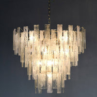 Textured glass four tiered chandelier on a gilt metal frame, a statement in any room. Sixteen bulbs glow through the glass, giving a diffused, ambient light. 