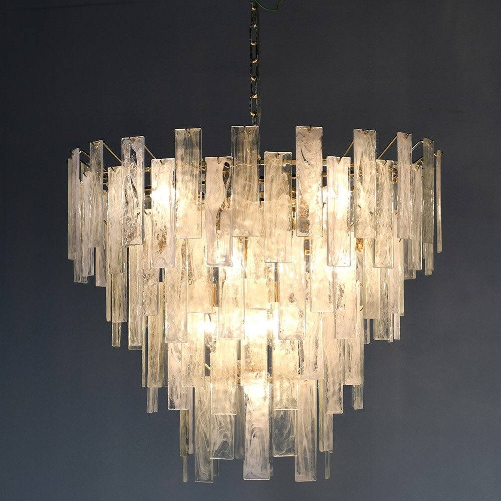 Textured glass four tiered chandelier on a gilt metal frame, a statement in any room. Sixteen bulbs glow through the glass, giving a diffused, ambient light. 