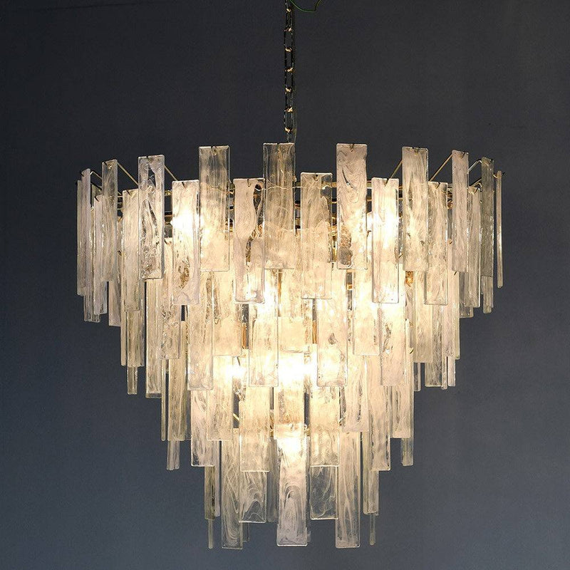 Textured glass four tiered chandelier on a gilt metal frame, a statement in any room. Sixteen bulbs glow through the glass, giving a diffused, ambient light. 