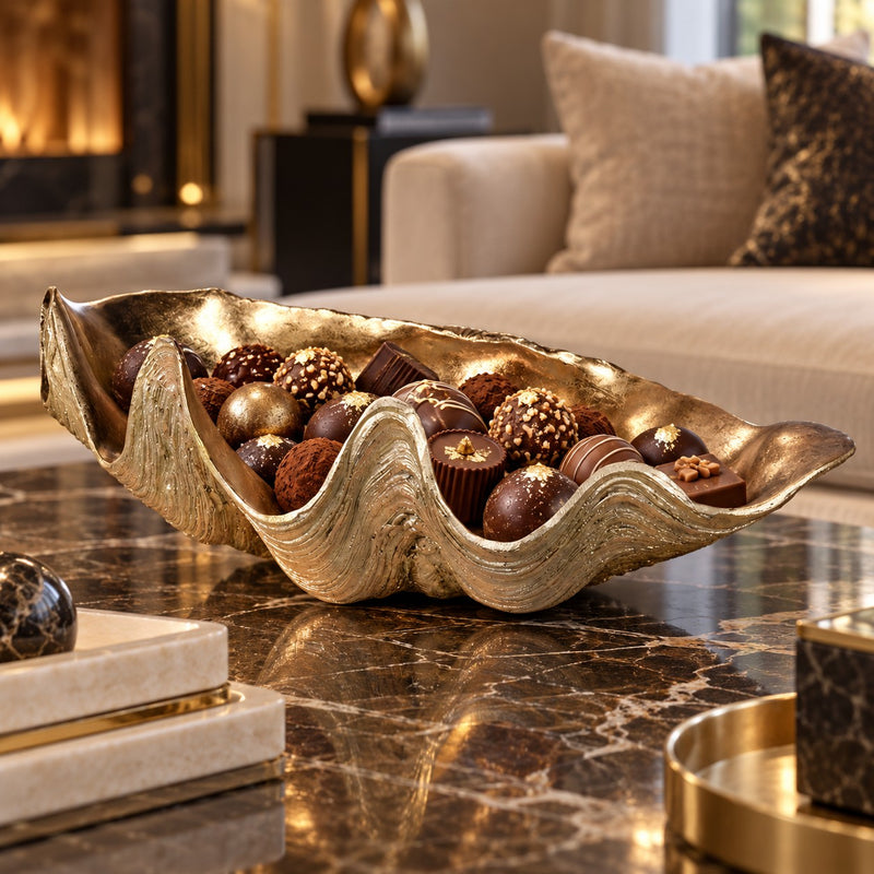 Gold shell holding chocolates on a marble coffee table in a living room.