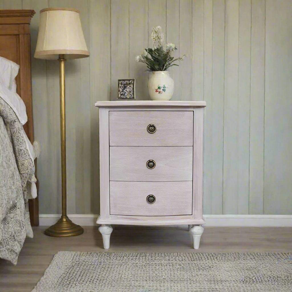 A solid hardwood three draw bedside table made from bleached mahogeny wood with ash veneers in a white wash finish. 