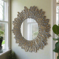 Large Round sun wall mirror with a distressed gold textured frame. The shape adds a touch of movement to its design. The distressed gold finish gives an antique feel against a pale wall next to window in a hall.
