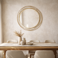 Circular swirl gilt mirror over a Scandi style dining table and chairs, in a bright dining room.