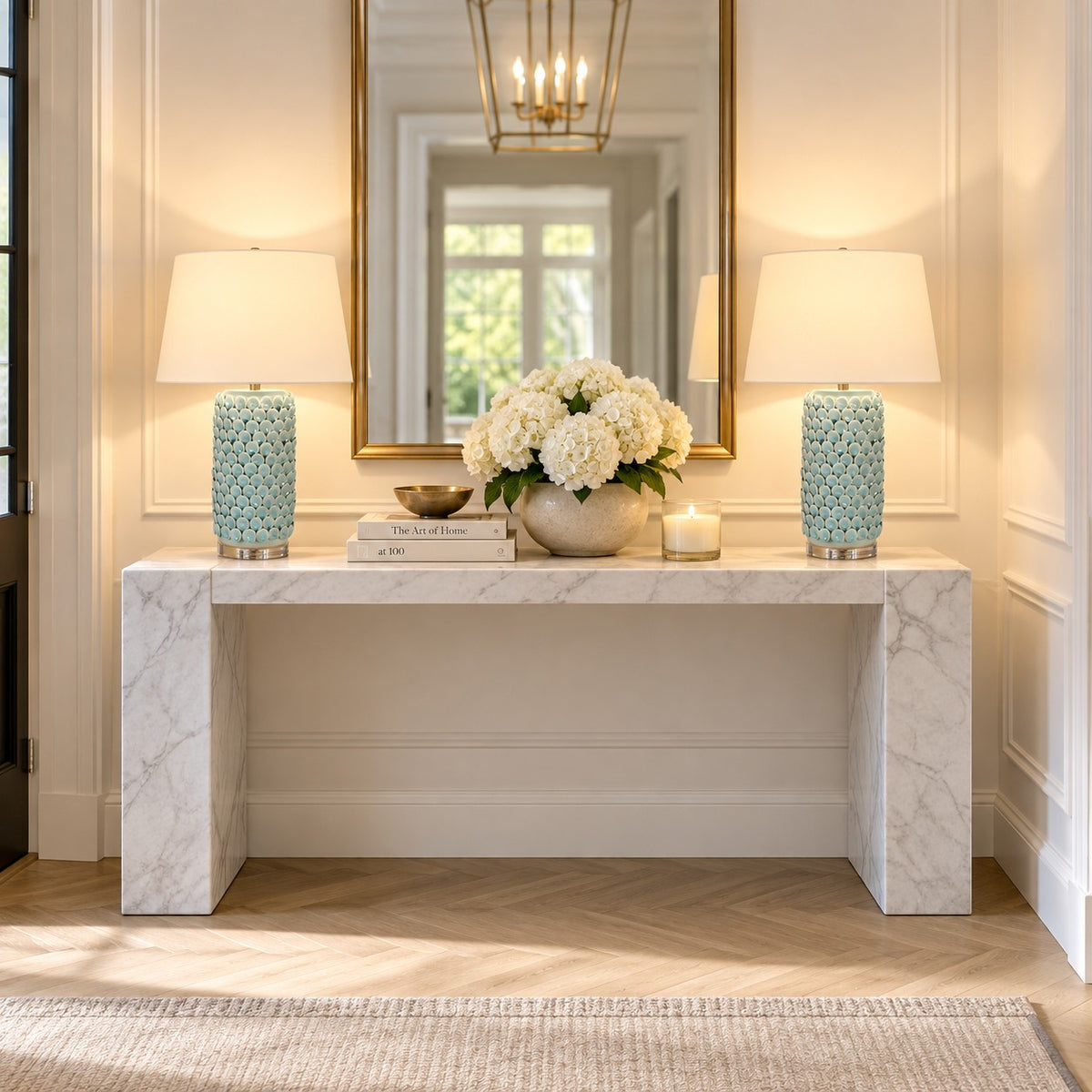 A symmetrical entryway scene featuring a white marble console table with two matching table lamps on either side.