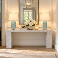 A symmetrical entryway scene featuring a white marble console table with two matching table lamps on either side.