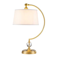 Table lamp with gold arm and white shade on a white background
