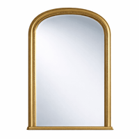 Tall gilt overmantle mirror with arched top, gold frame above fireplace in traditional country home hallway