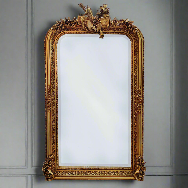 Beautifully ornate large ornate gilt wood wall mirror.The gold frame is decorated, in the Georgian style with musical instruments, swags and other embellishments. Exceptionally ornate frame of large dimensions, perfect in a period country house, or an elegant town home. The addition of a mirror of this quality to a room immediately conjures up a luxurious air to a home.