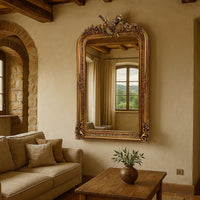 Tall ornate gold-framed wall mirror with detailed French Rococo-style carving and decorative crest.