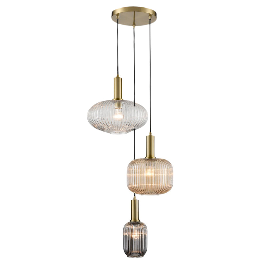 A modern three-light cascading pendant ceiling fixture with ribbed glass shades in clear, warm beige, and smoky gray, accented with brushed brass hardware.
