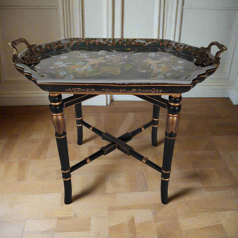 Close-up of a luxury porcelain tray table with hand-painted birds and foliage, ornate bronze handles, and a black wood stand with gold gilt bamboo detailing on parquet flooring.