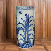 Large blue and white porcelain umbrella stand featuring traditional botanical and dragon motifs, glazed ceramic finish, cylindrical shape. 