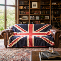 Large vintage-style Union Jack textile wall hanging in muted navy, red and cream, displayed horizontally above a dark blue velvet Chesterfield sofa.