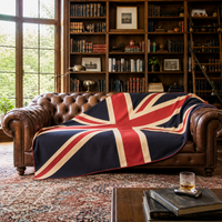 Large vintage-style Union Jack textile wall hanging in muted navy, red and cream, displayed horizontally above a dark blue velvet Chesterfield sofa.