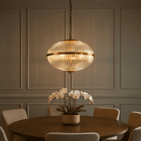 Vintage ribbed glass globe ceiling light with brushed brass finish hanging over a dining table