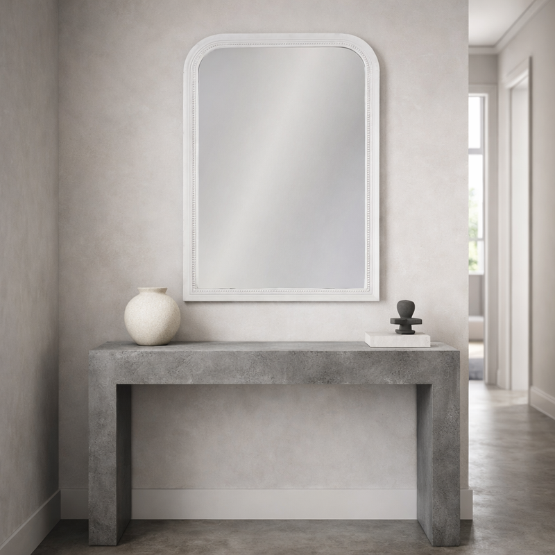 Concrete console table with the vintage white mirror and decorative items in a modern interior setting.
