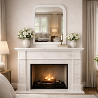 Vintage white beaded overmantle mirror
 over a fireplace in a bedroom, with neutral coloured walls and textiles.