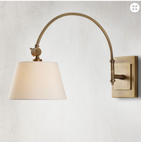 Brass wall sconce with a white shade on a light gray background